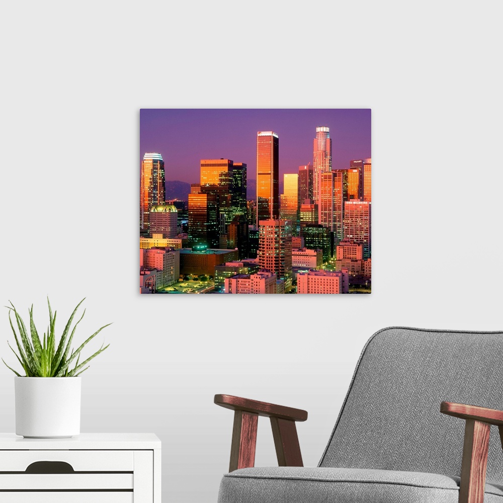 A modern room featuring Landscape, close up photograph on a large wall hanging of brightly lit skyscrapers in downtown Lo...