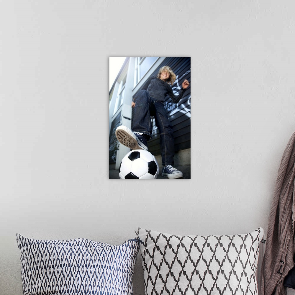 A bohemian room featuring Low angle portrait view  of blond boy with football.