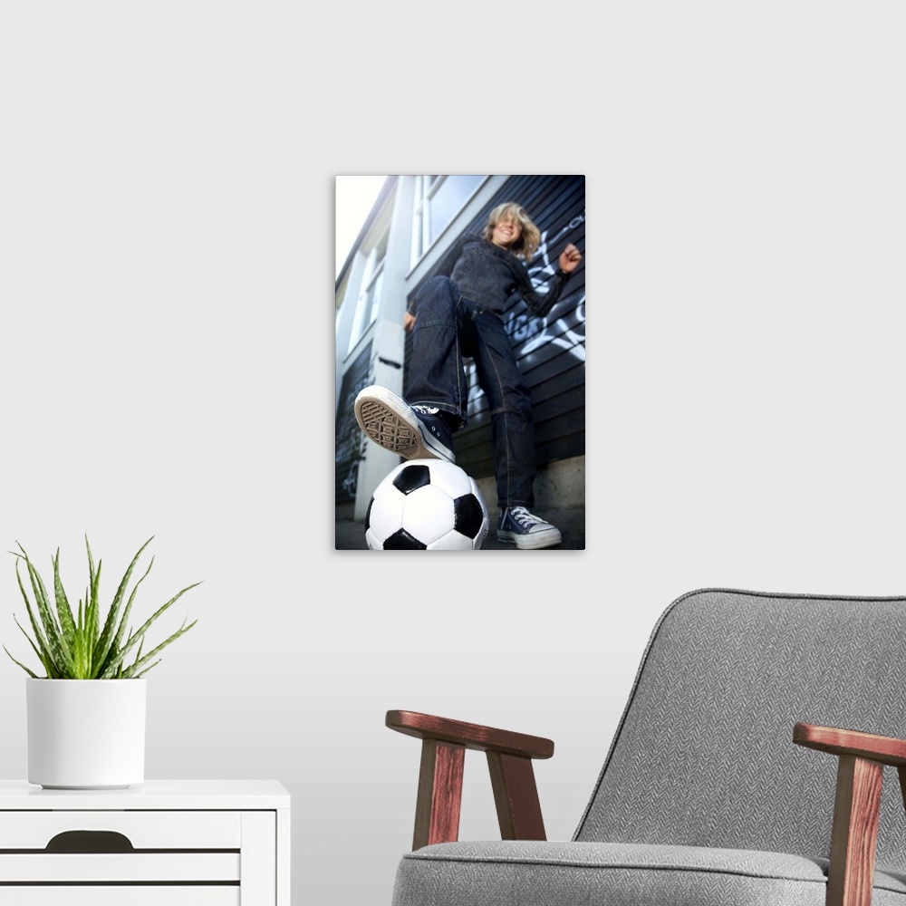 A modern room featuring Low angle portrait view  of blond boy with football.