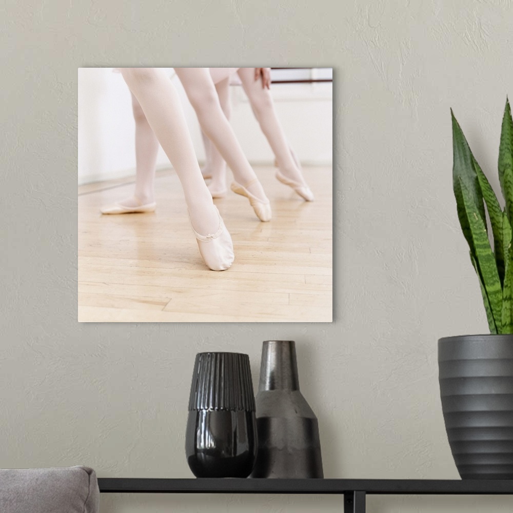 A modern room featuring Low Section of Three Girls in Ballet Shoes Standing With Their Leg Pointing out