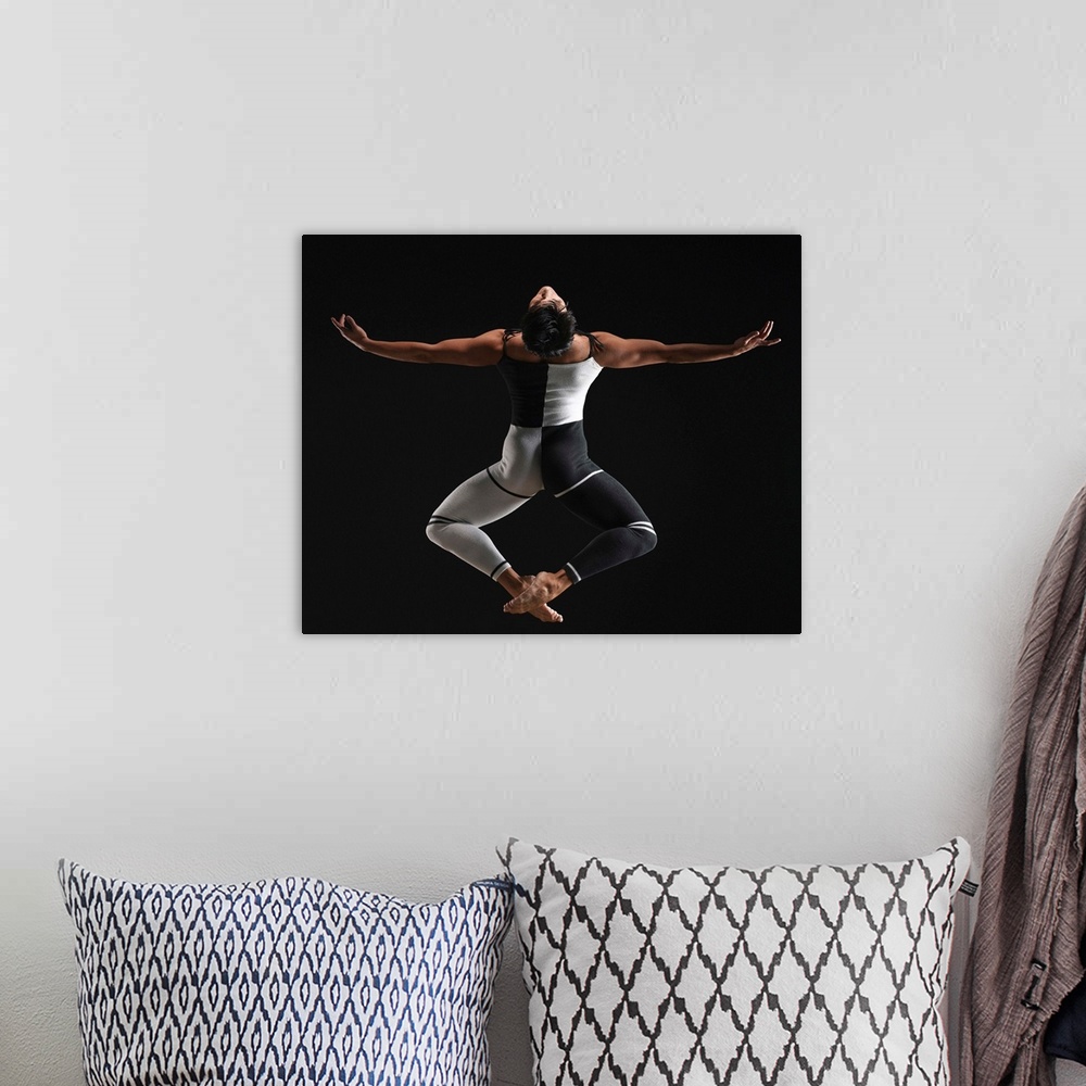 A bohemian room featuring Male ballet dancer in mid air pose, arms extended, rear view