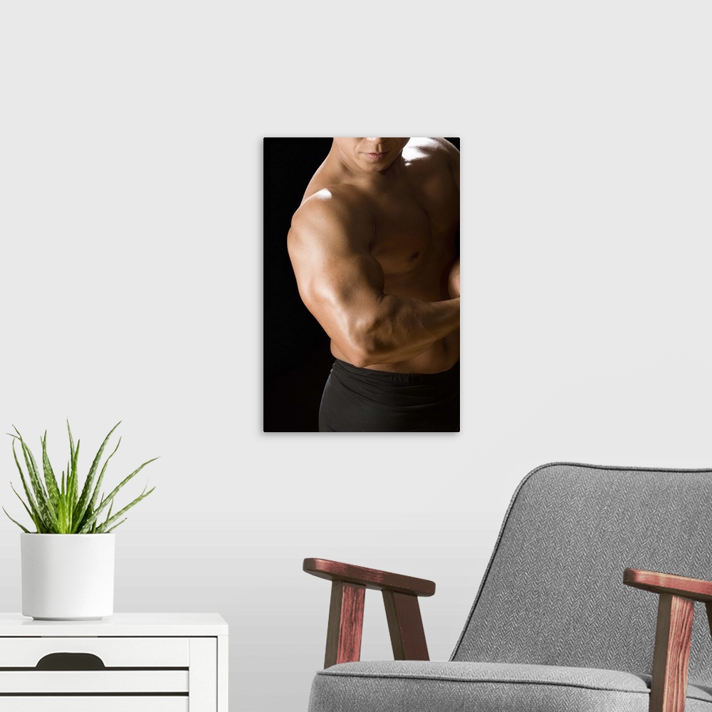 A modern room featuring Male bodybuilder flexing muscles, front view, black background