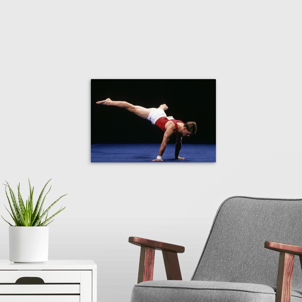 A modern room featuring Male gymnast peforming a routine in the floor exercise