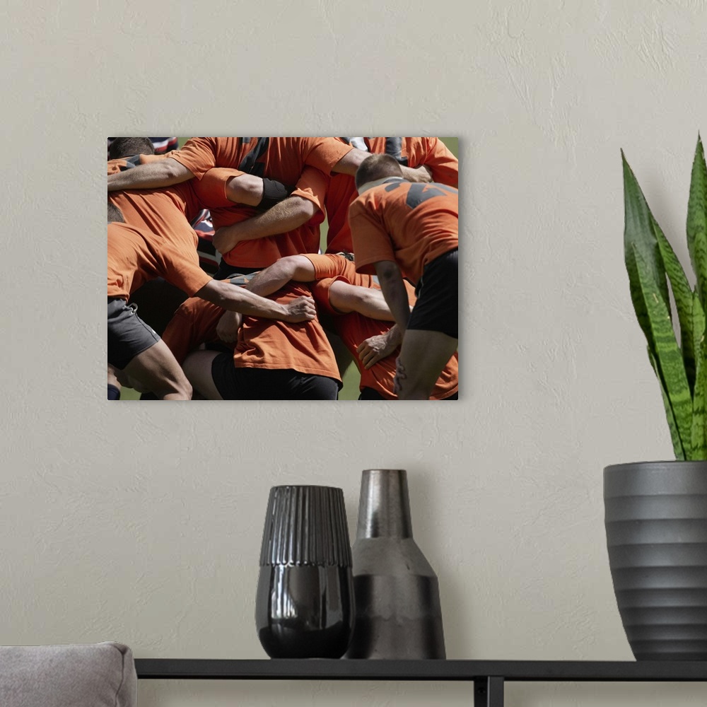 A modern room featuring Male rugby players in scrum, rear view