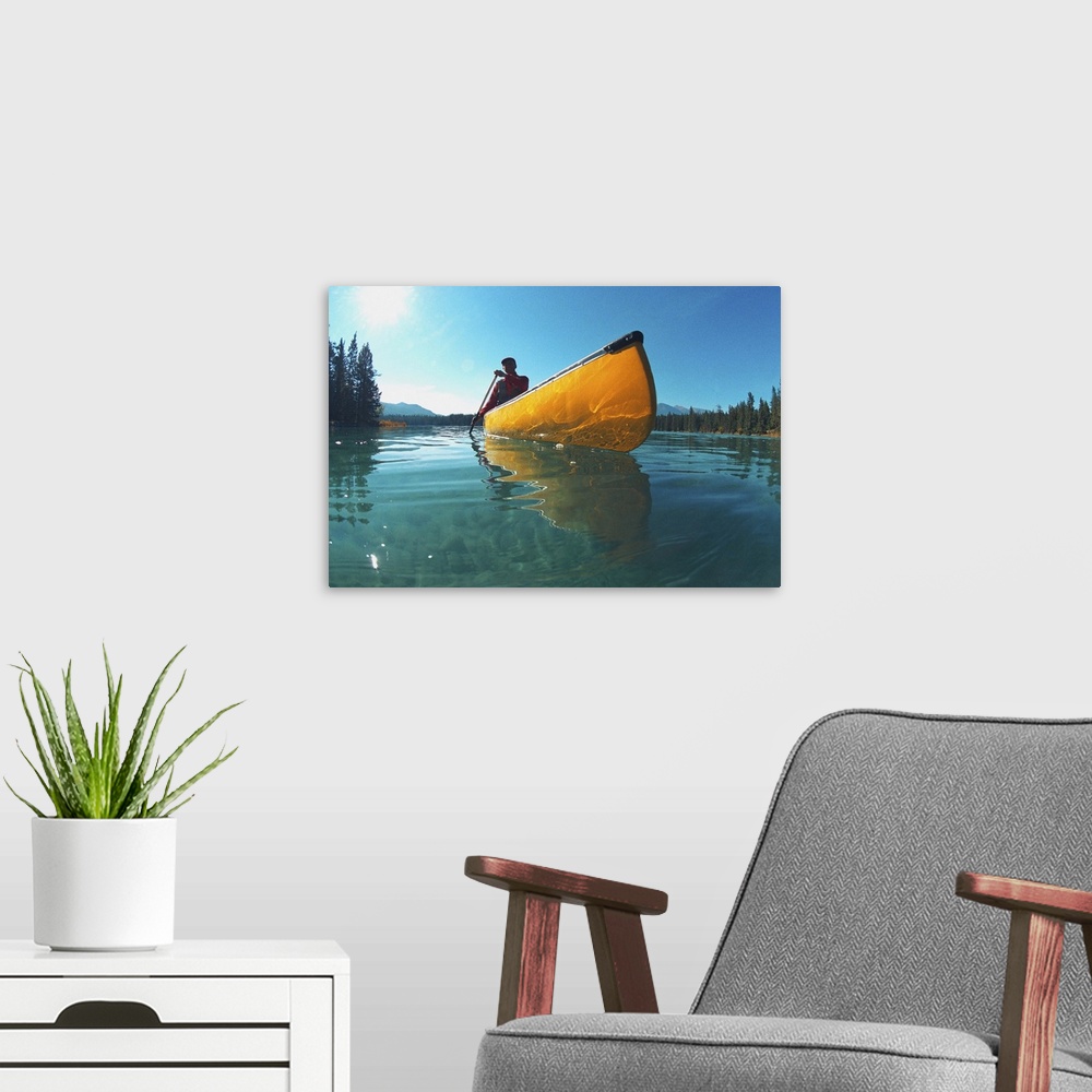 A modern room featuring Man in yellow canoe on lake