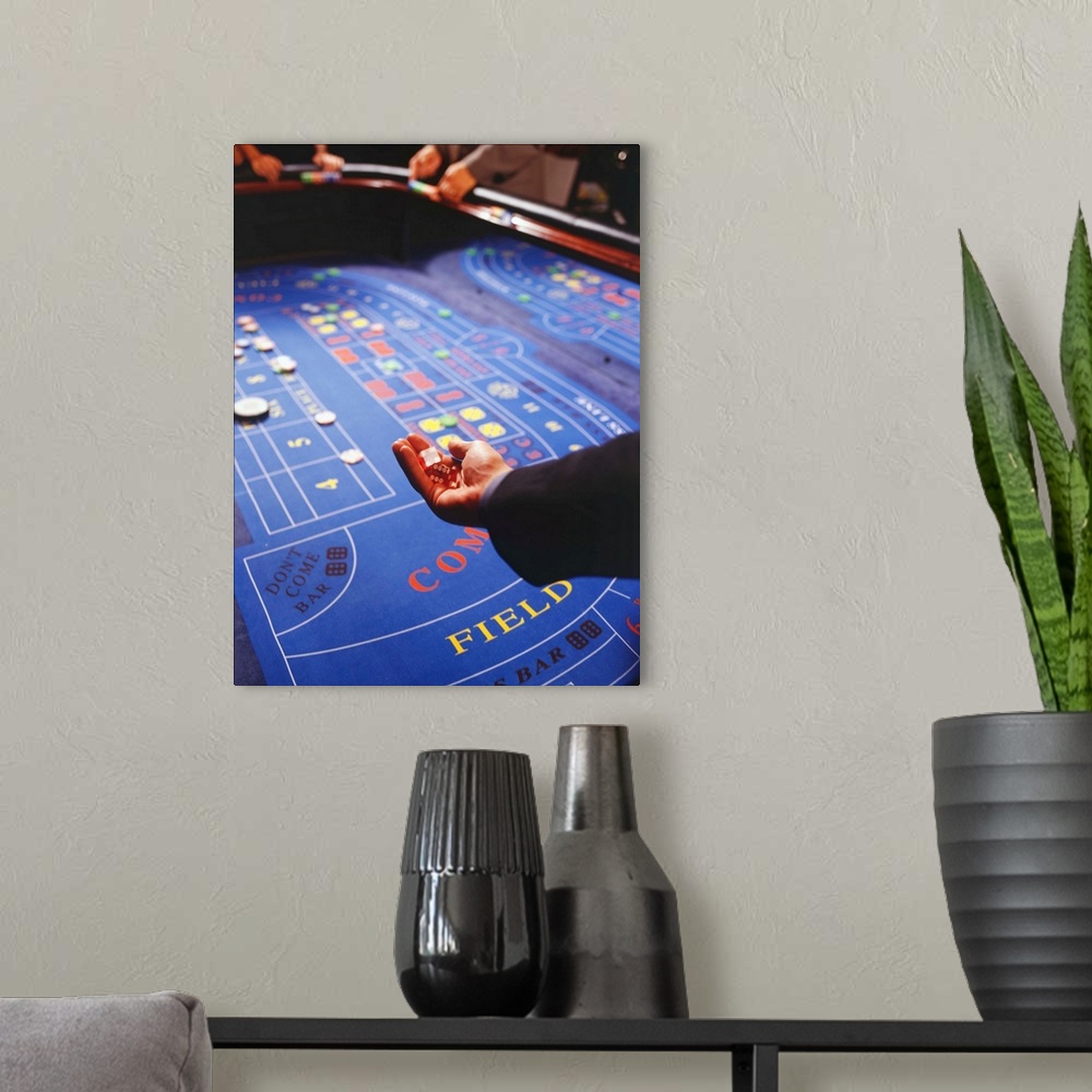 A modern room featuring Man shaking dice during game of craps in casino