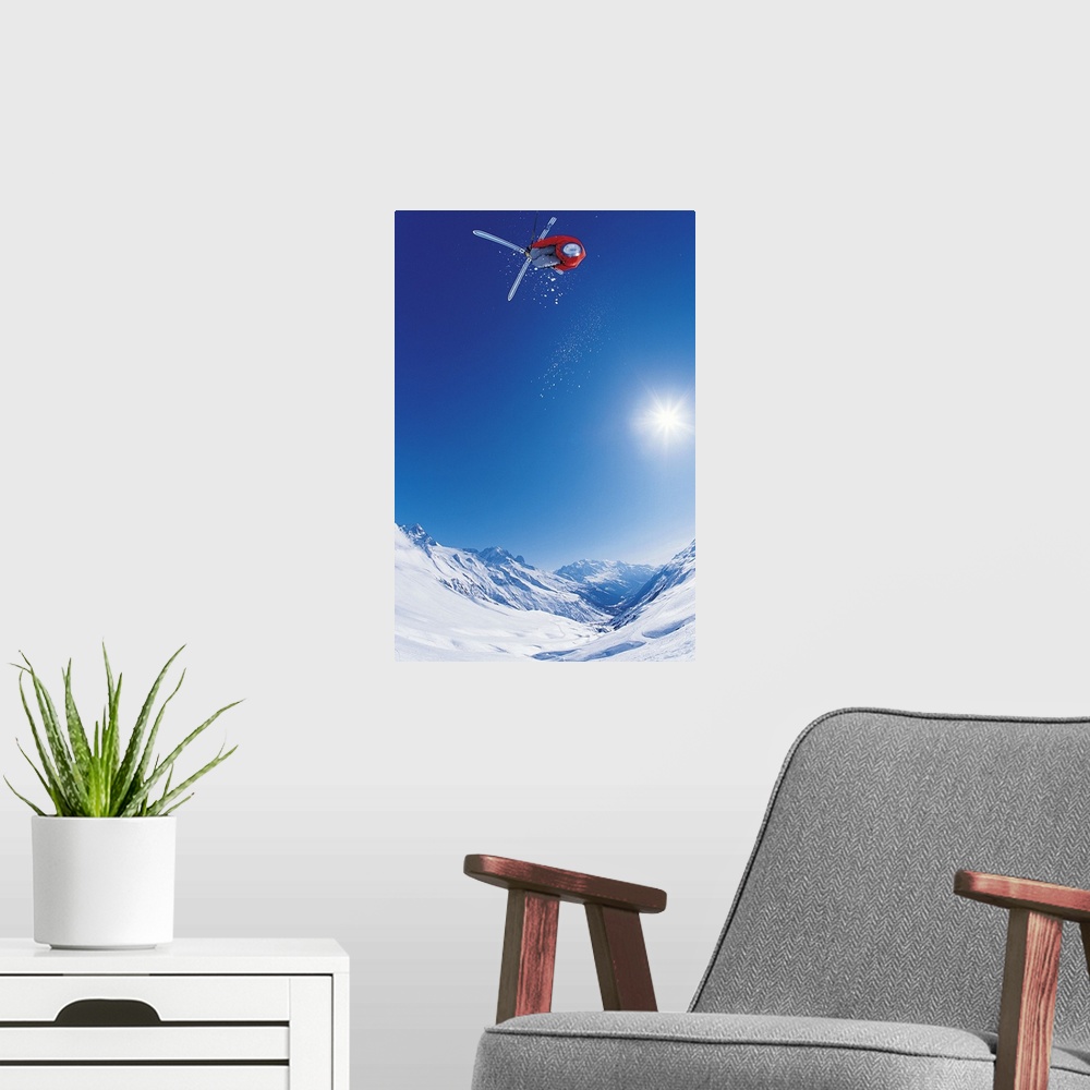 A modern room featuring Vertical photo of a man crossing his skis on as he flies through the air as the sun shines down o...