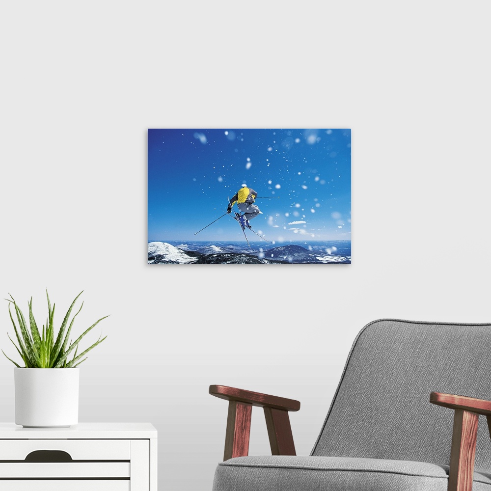 A modern room featuring Photograph of man on skis in mid air jump over snow covered mountains.
