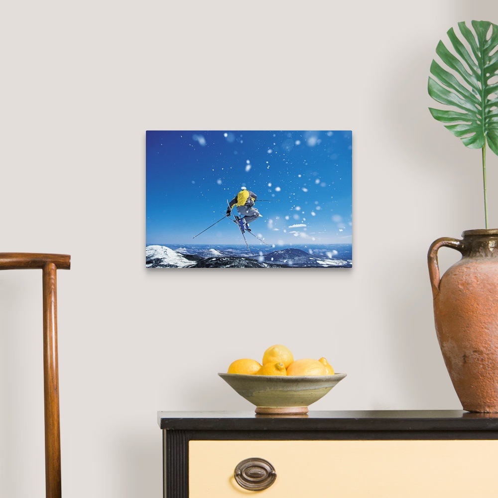 A traditional room featuring Photograph of man on skis in mid air jump over snow covered mountains.