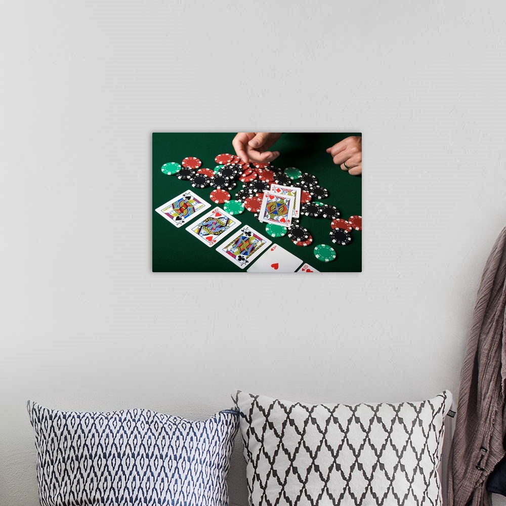 A bohemian room featuring Man throwing playing cards onto pile of poker chips