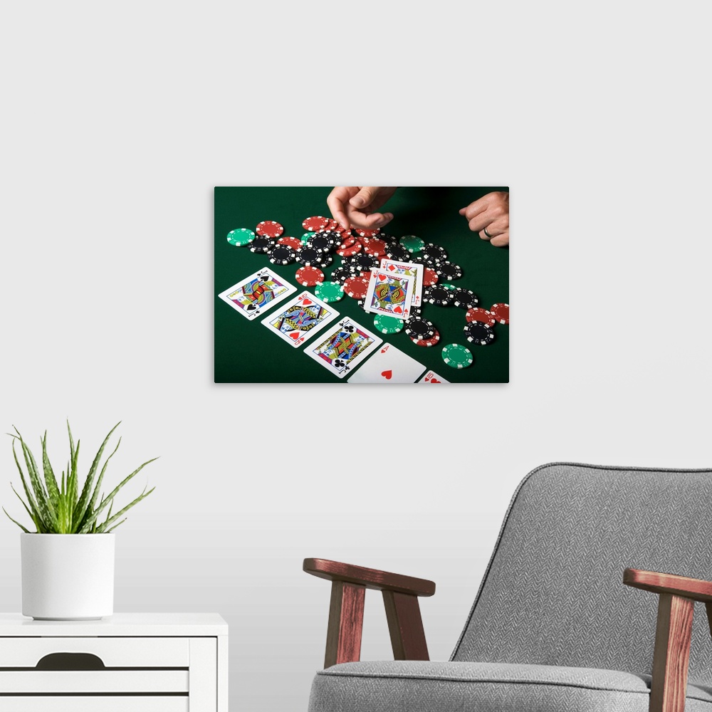 A modern room featuring Man throwing playing cards onto pile of poker chips