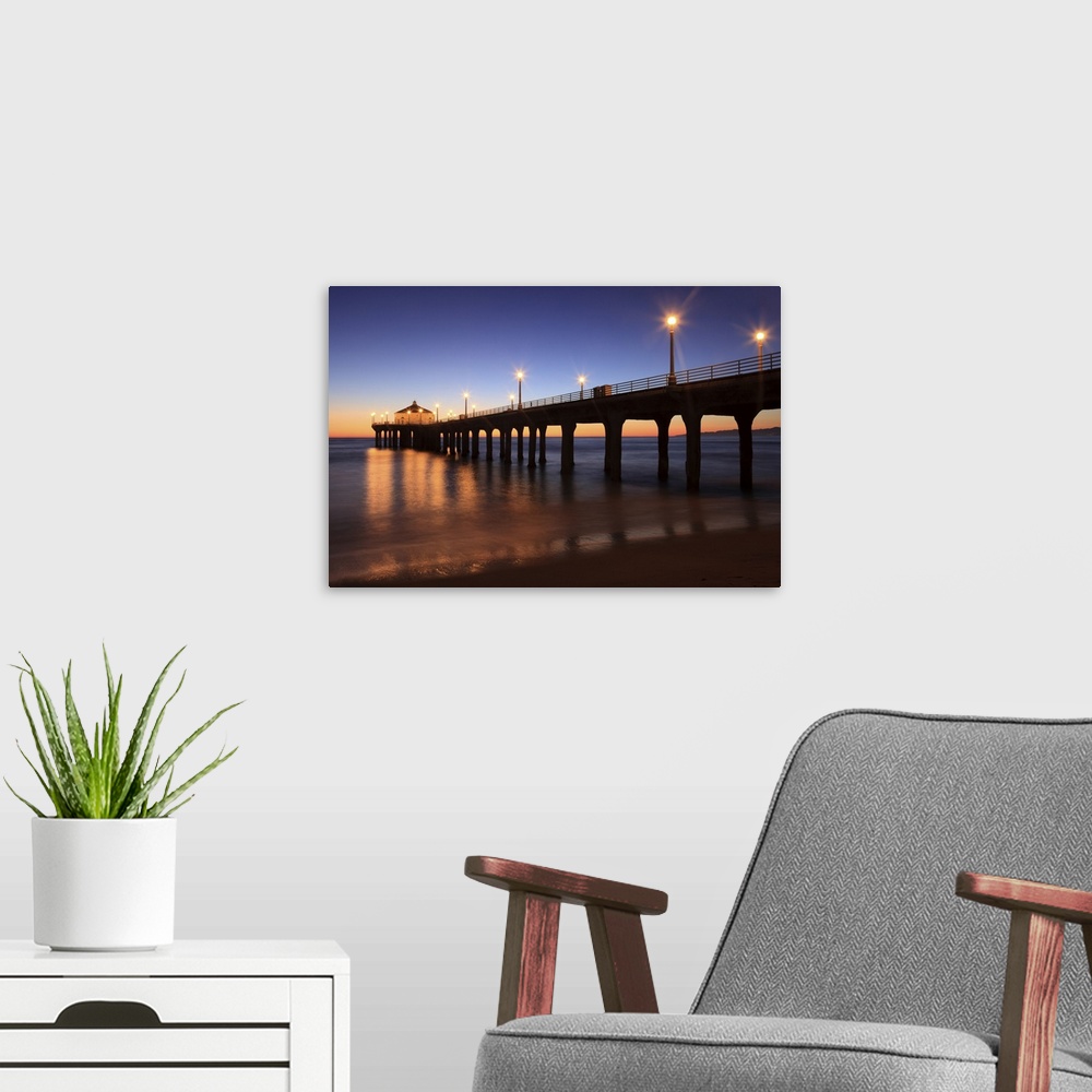A modern room featuring Big canvas print of a pier that is silhouetted against a sunset with lights lit up along it.