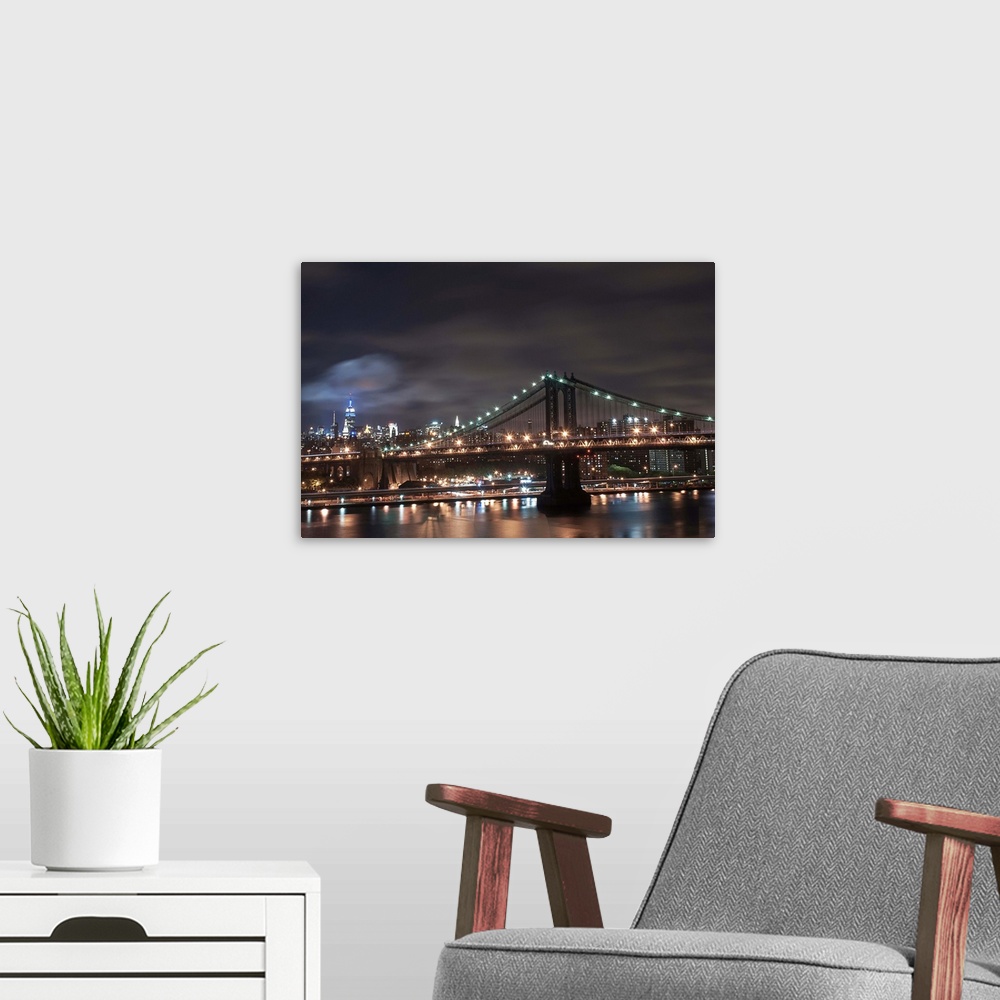 A modern room featuring Night time long exposure taken from the Brooklyn Bridge facing uptown looking at the Manhattan Br...