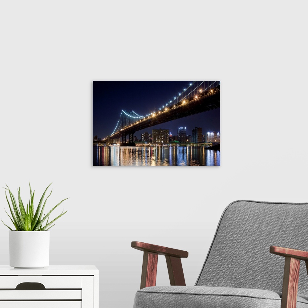 A modern room featuring USA, New York, Brooklyn, Manhattan Bridge at night reflected in East River with Empire State Buil...