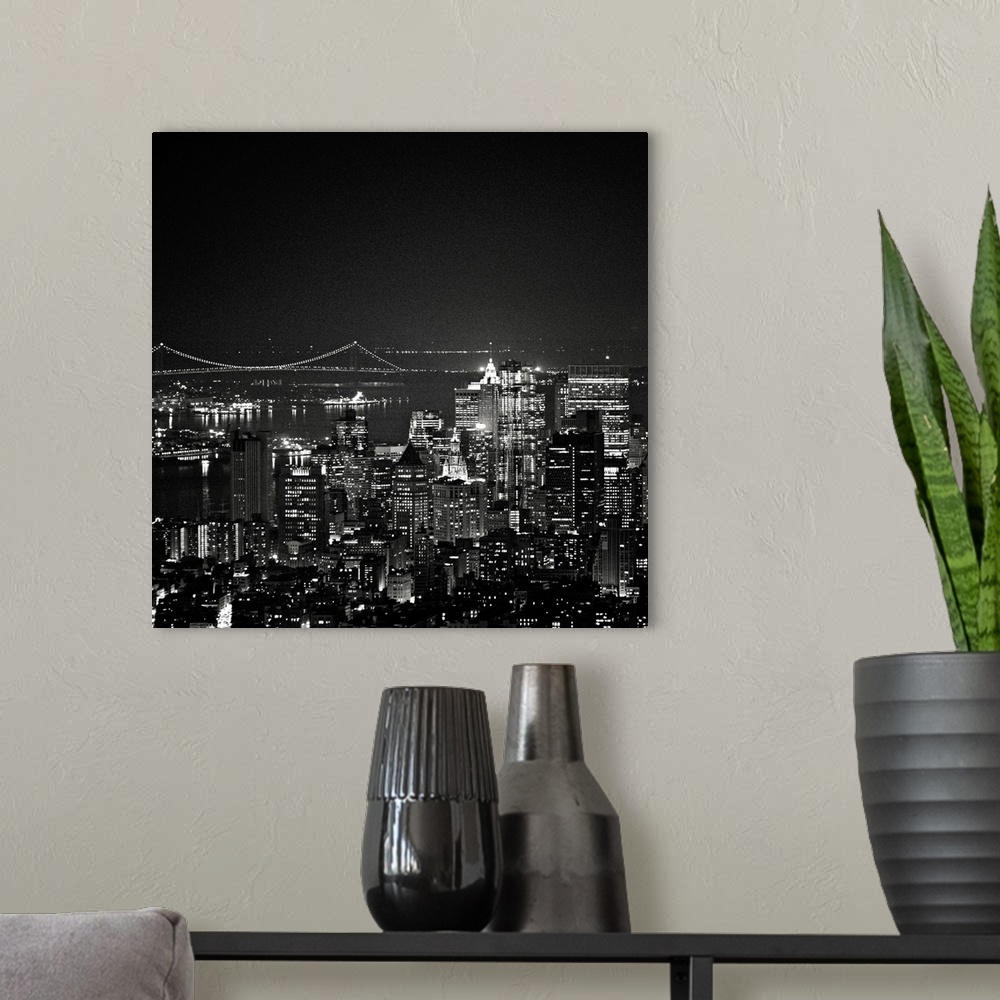 A modern room featuring This square piece is an aerial photograph taken of skyscrapers in New York illuminated under a da...