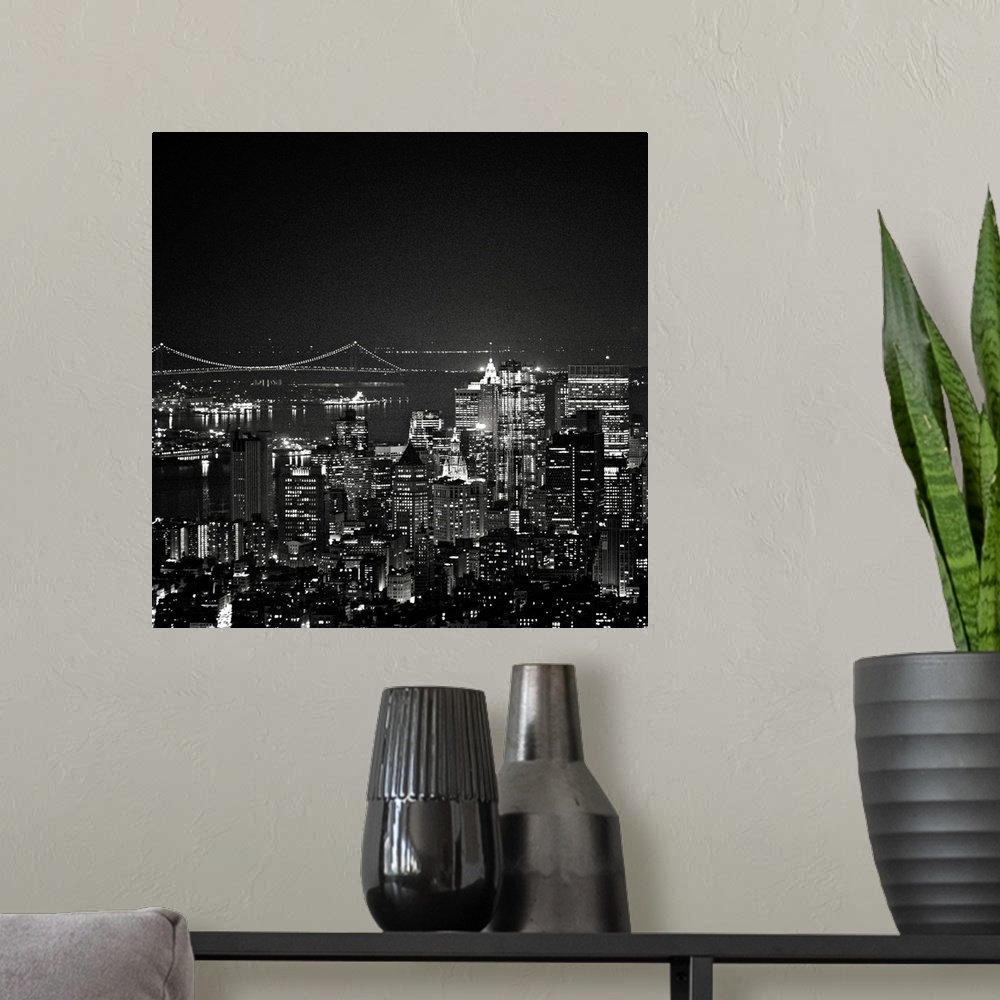 A modern room featuring This square piece is an aerial photograph taken of skyscrapers in New York illuminated under a da...
