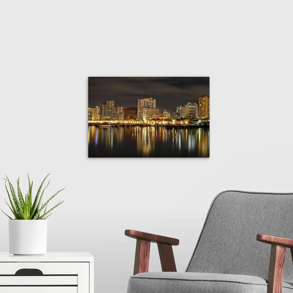 A modern room featuring Wall docor of a city in the Philippines illuminated at night reflected on the water.