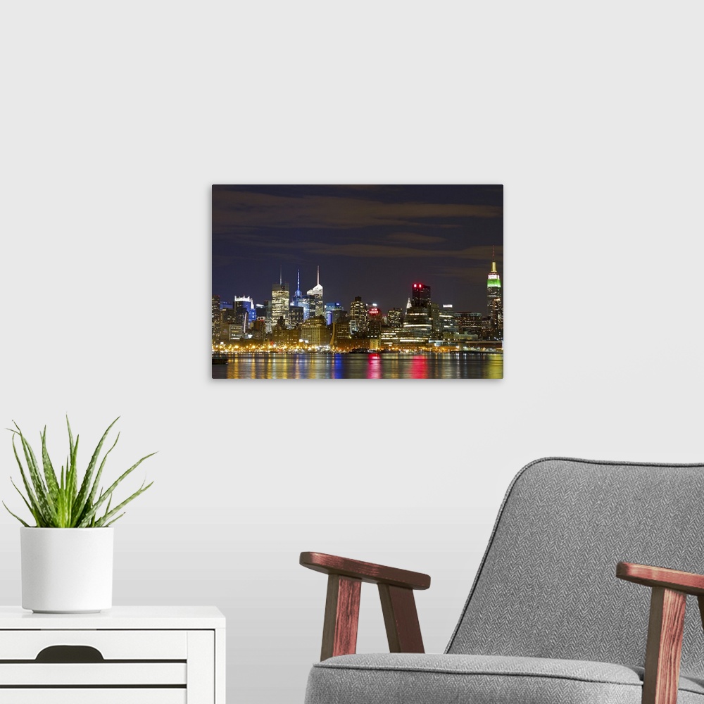 A modern room featuring Giant landscape photograph of the brightly lit Manhattan skyline at night, reflecting in the water.
