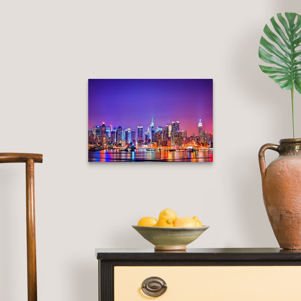 A traditional room featuring Photograph of New York skyline at night with the Hudson River in foreground.  The building lights...