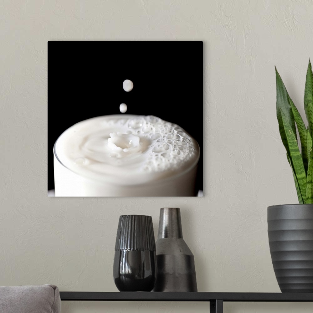 A modern room featuring Milk drops emerging on a glass of milk after pouring against black background, UK.