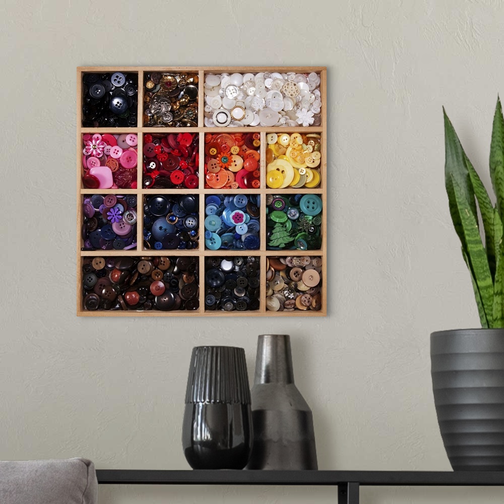 A modern room featuring Modern and antique buttons sorted by color in divided wooden tray.