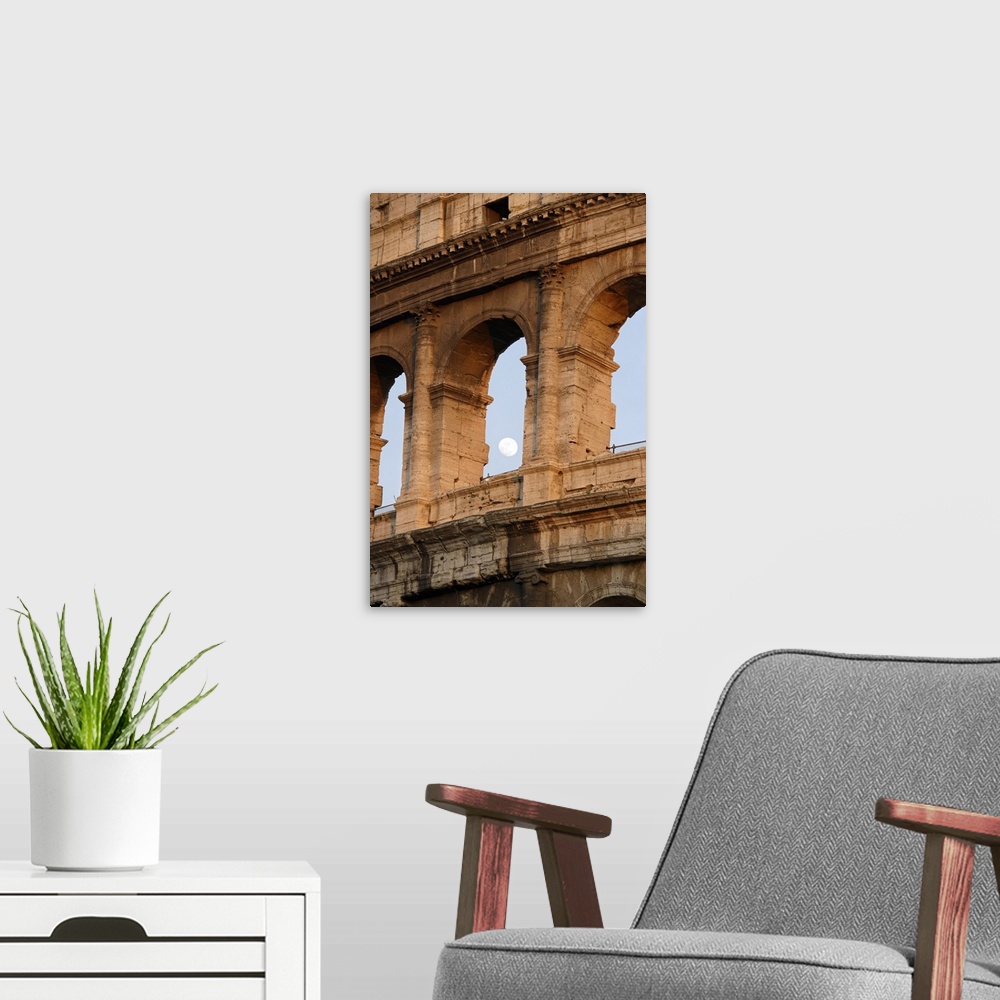 A modern room featuring Vertical photo on canvas of the moon shining through an opening of one of the arches in the Colos...