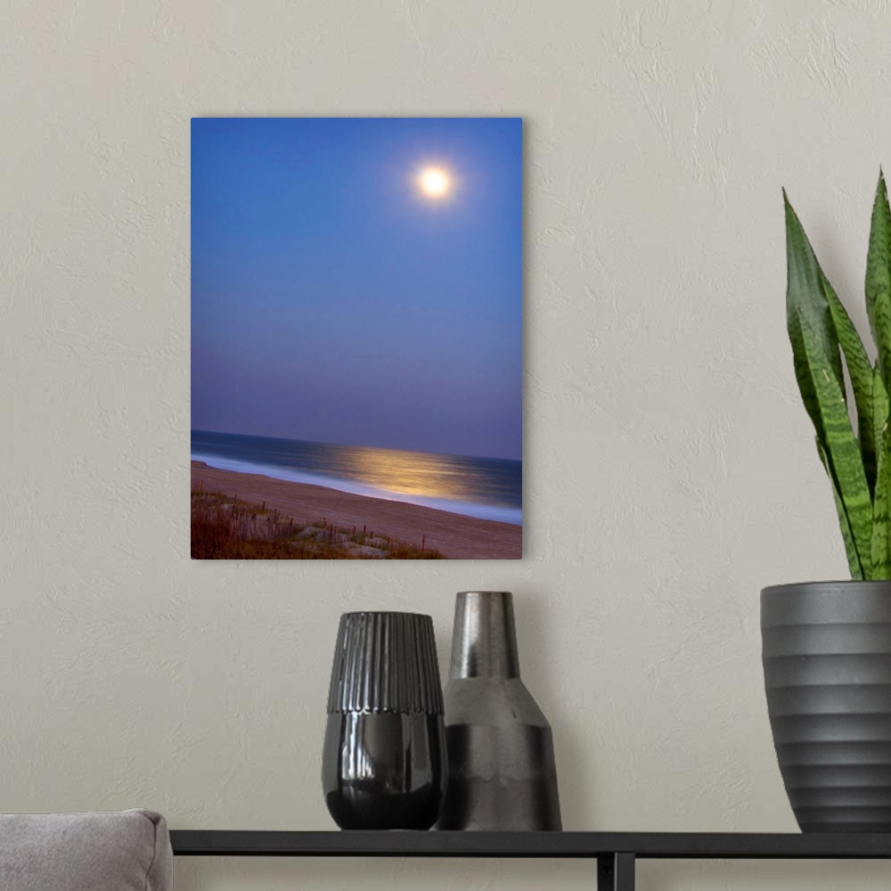 A modern room featuring This large piece is a picture of the moon shining brightly over the beach and reflecting in the o...