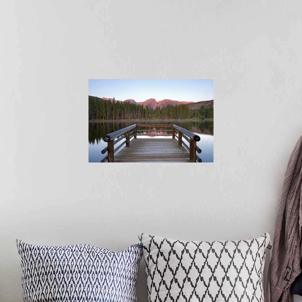 A bohemian room featuring A picture taken from a small dock that sits on a lake and looks out onto a mountainous view and t...