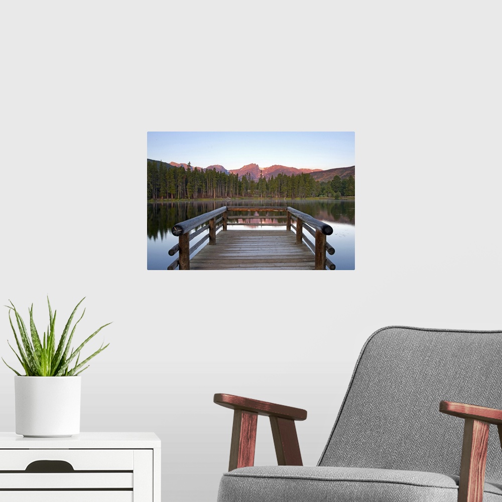 A modern room featuring A picture taken from a small dock that sits on a lake and looks out onto a mountainous view and t...