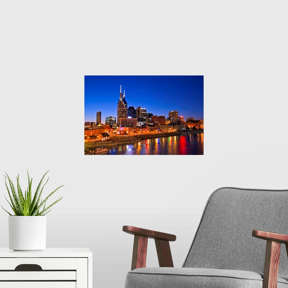 A modern room featuring Big, horizontal photograph of the Nashville Tennessee skyline, lit up during blue hour, just afte...