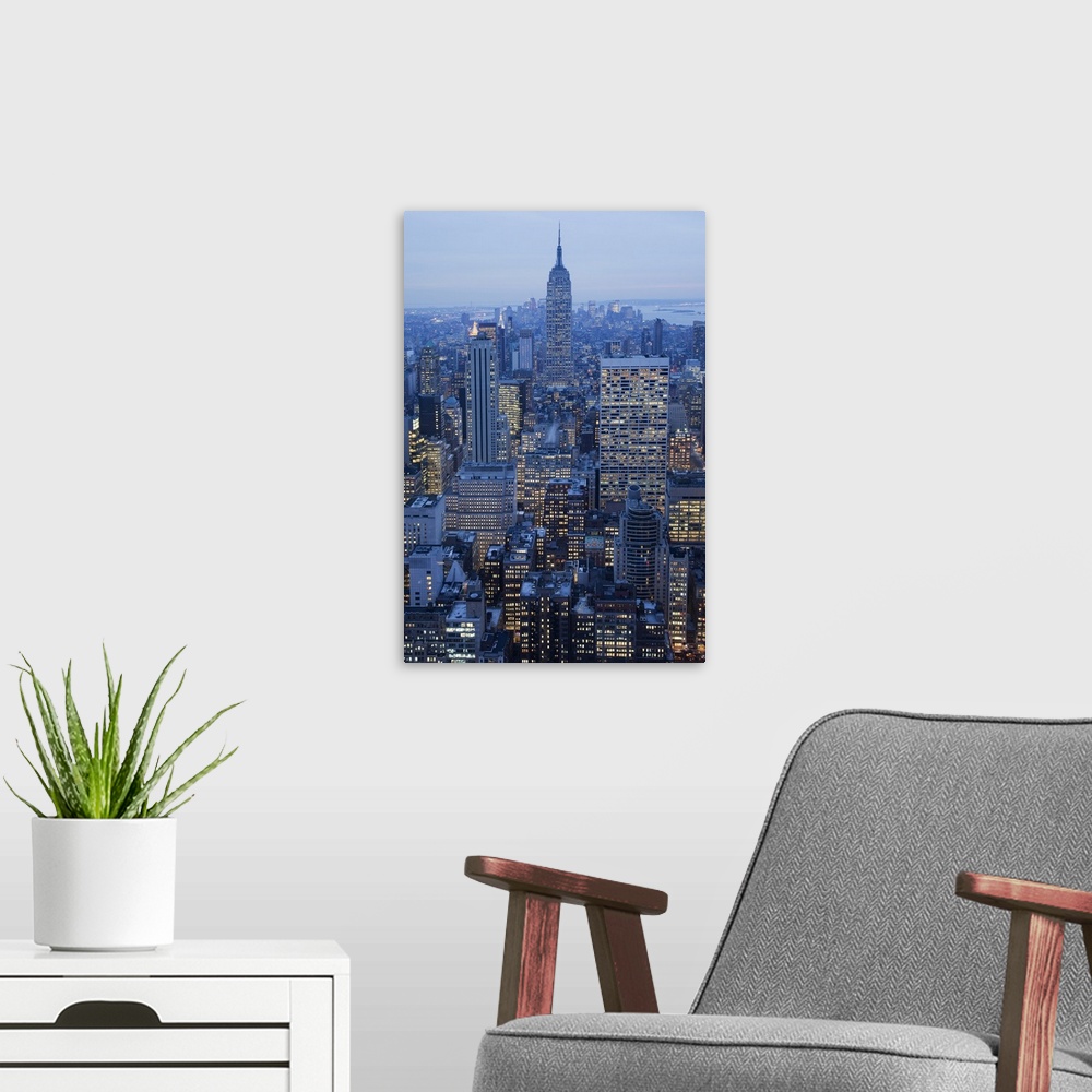 A modern room featuring Large vertical photograph of NYC taken at dusk with the Empire State Buiding center and many othe...