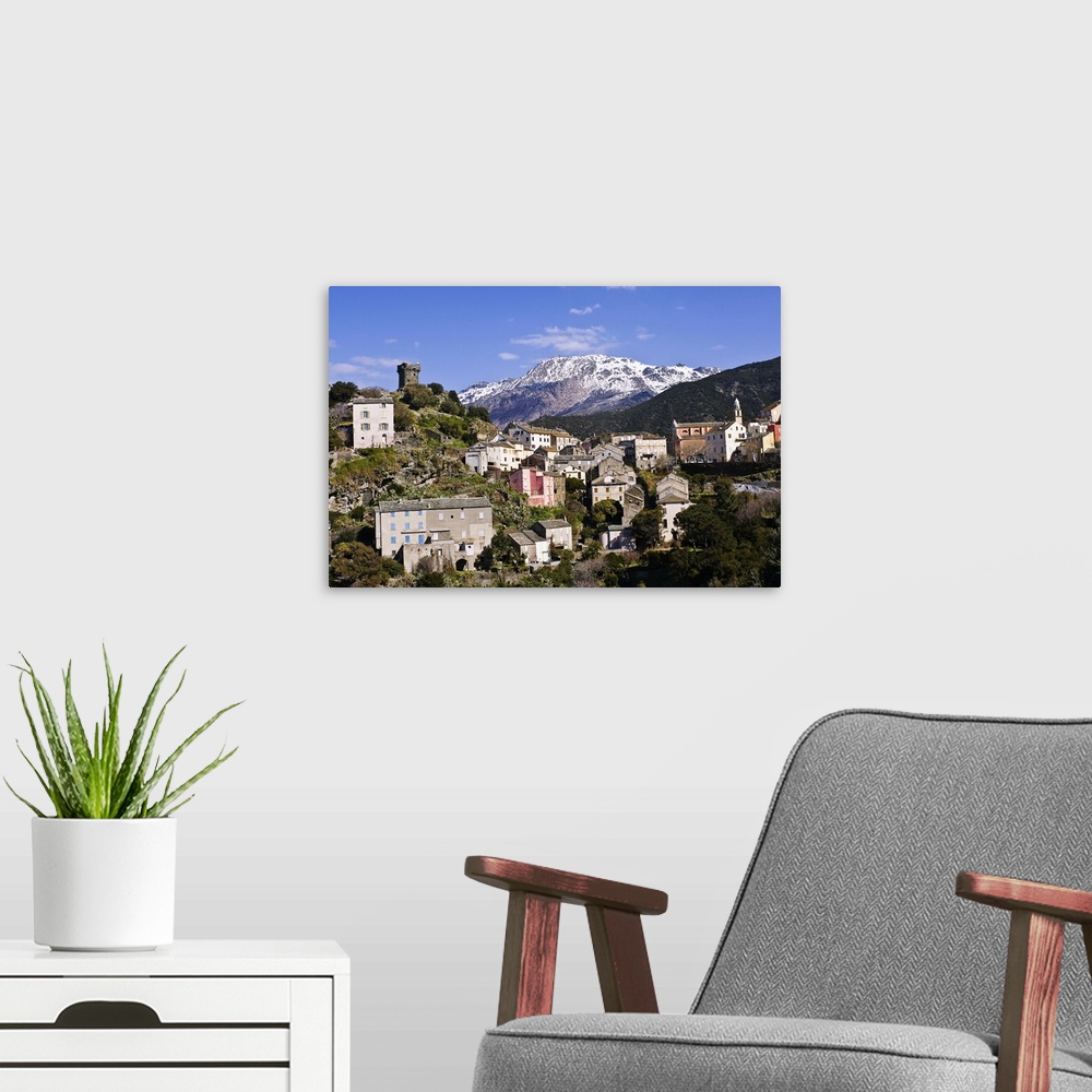 A modern room featuring Nonza village (Corsica, France) with its famous tower in the foreground. In the background, the m...