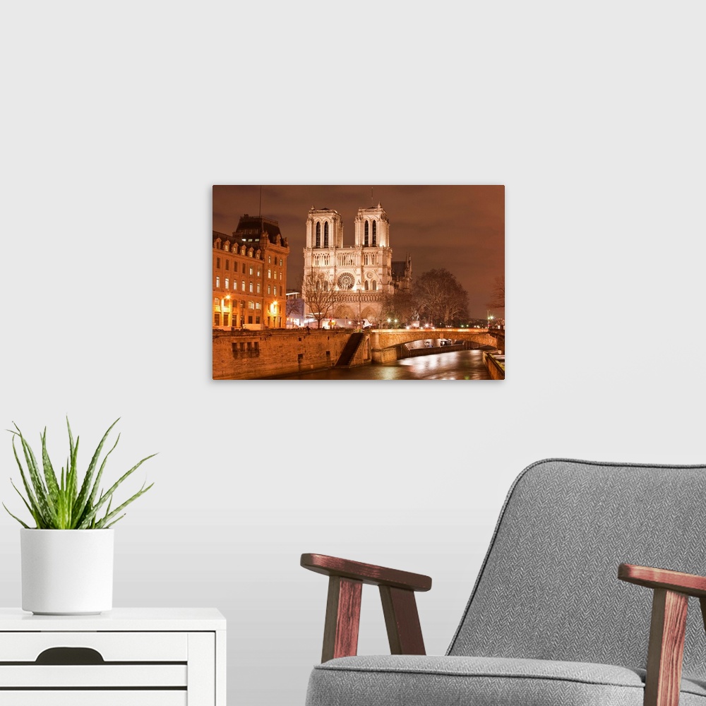 A modern room featuring Notre Dame de Paris cathedral at night.