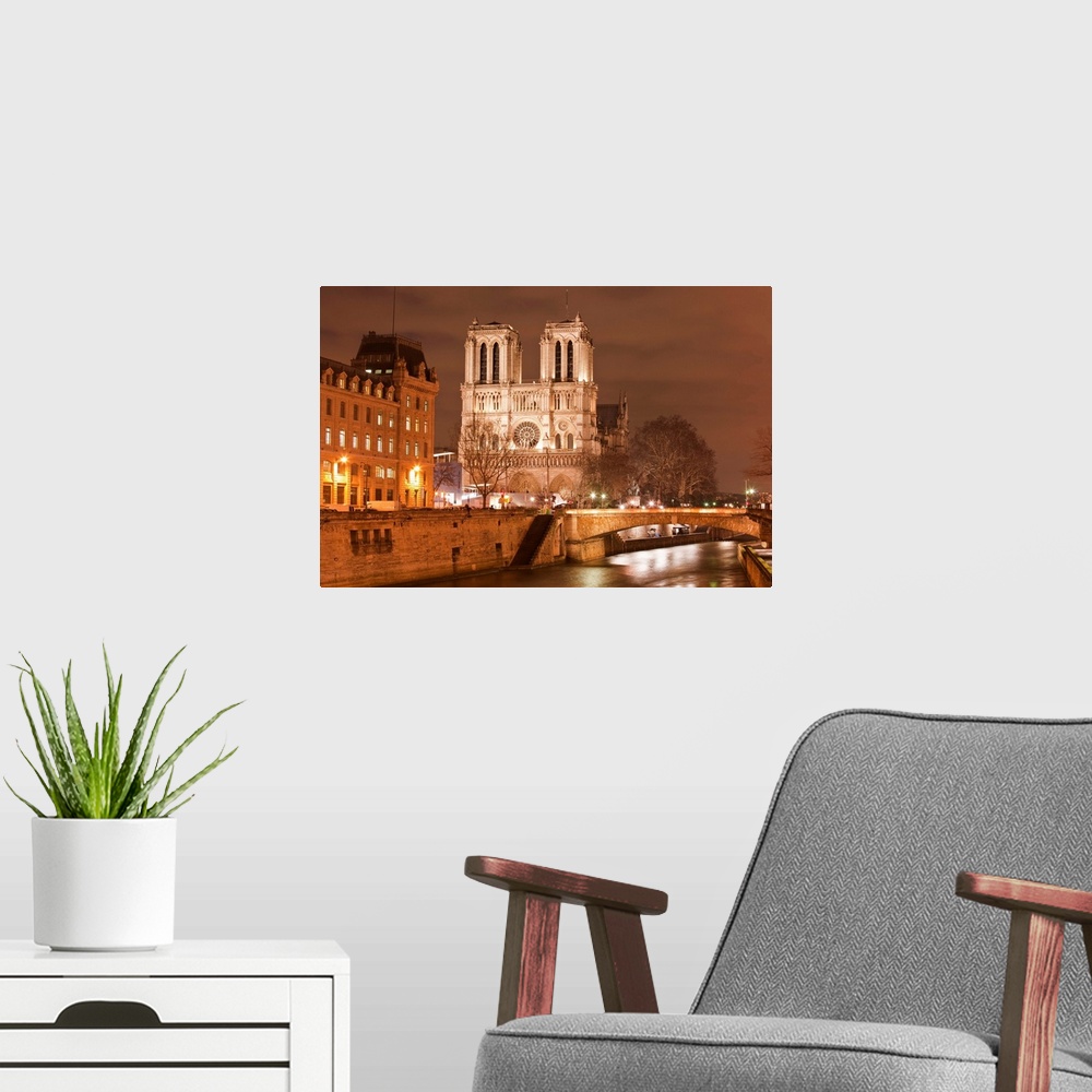 A modern room featuring Notre Dame de Paris cathedral at night.