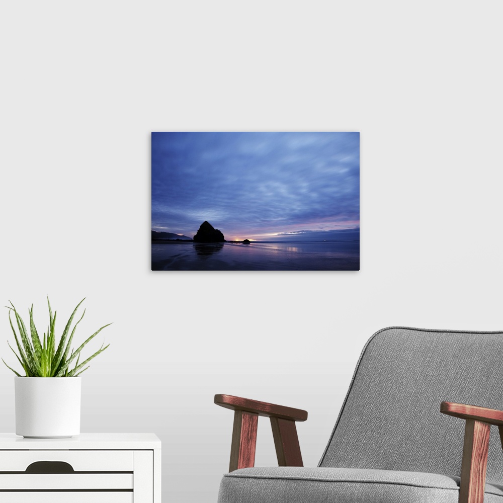 A modern room featuring Pacific ocean, Cannon Beach, OR after the sunset. Small yellow light on the horizon is a lighthou...