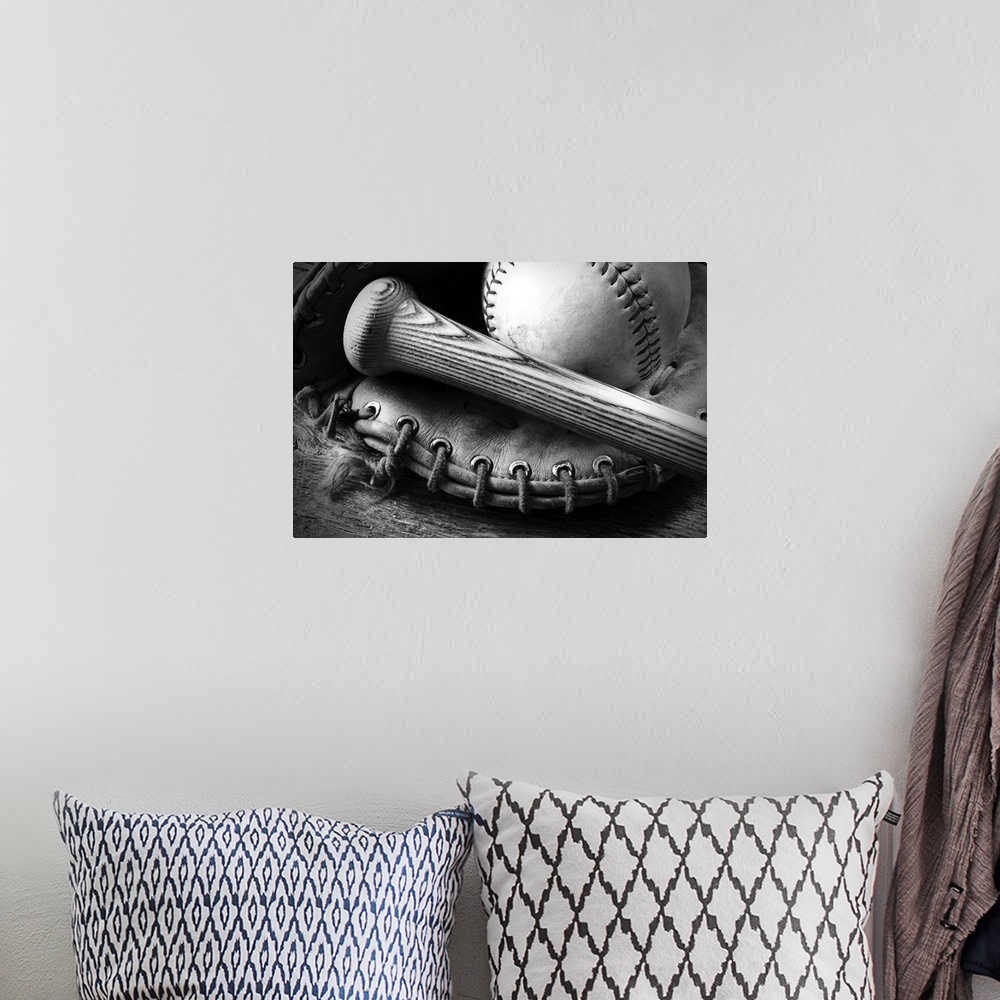 A bohemian room featuring A black and white image of an old baseball glove and bat.