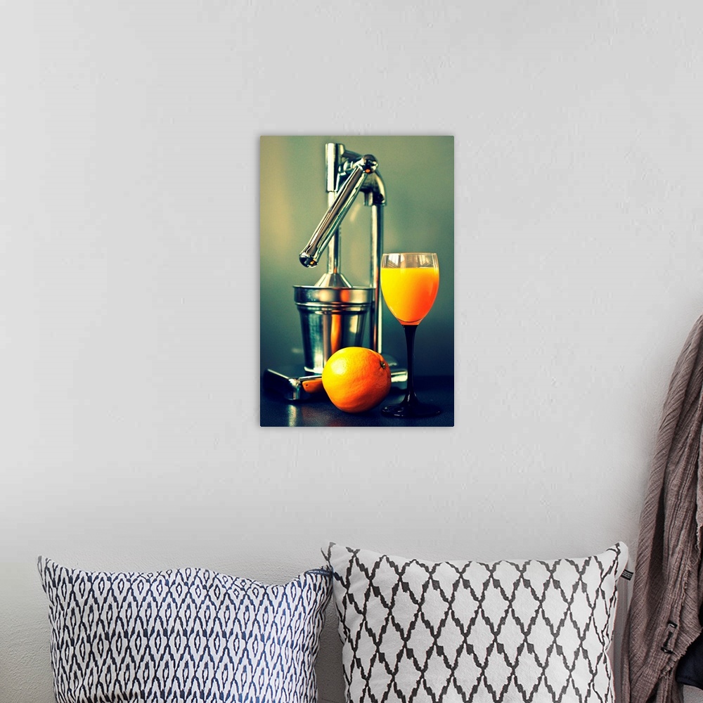 A bohemian room featuring Orange juice in glass, juicer and orange.