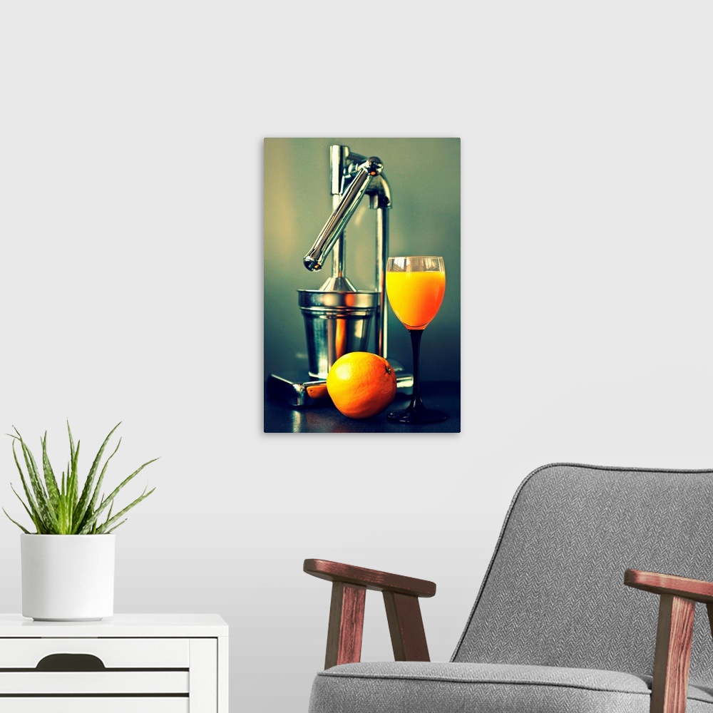 A modern room featuring Orange juice in glass, juicer and orange.