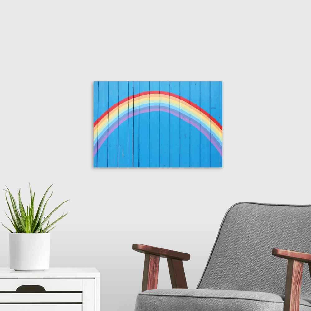A modern room featuring Painted rainbow on wooden fence.