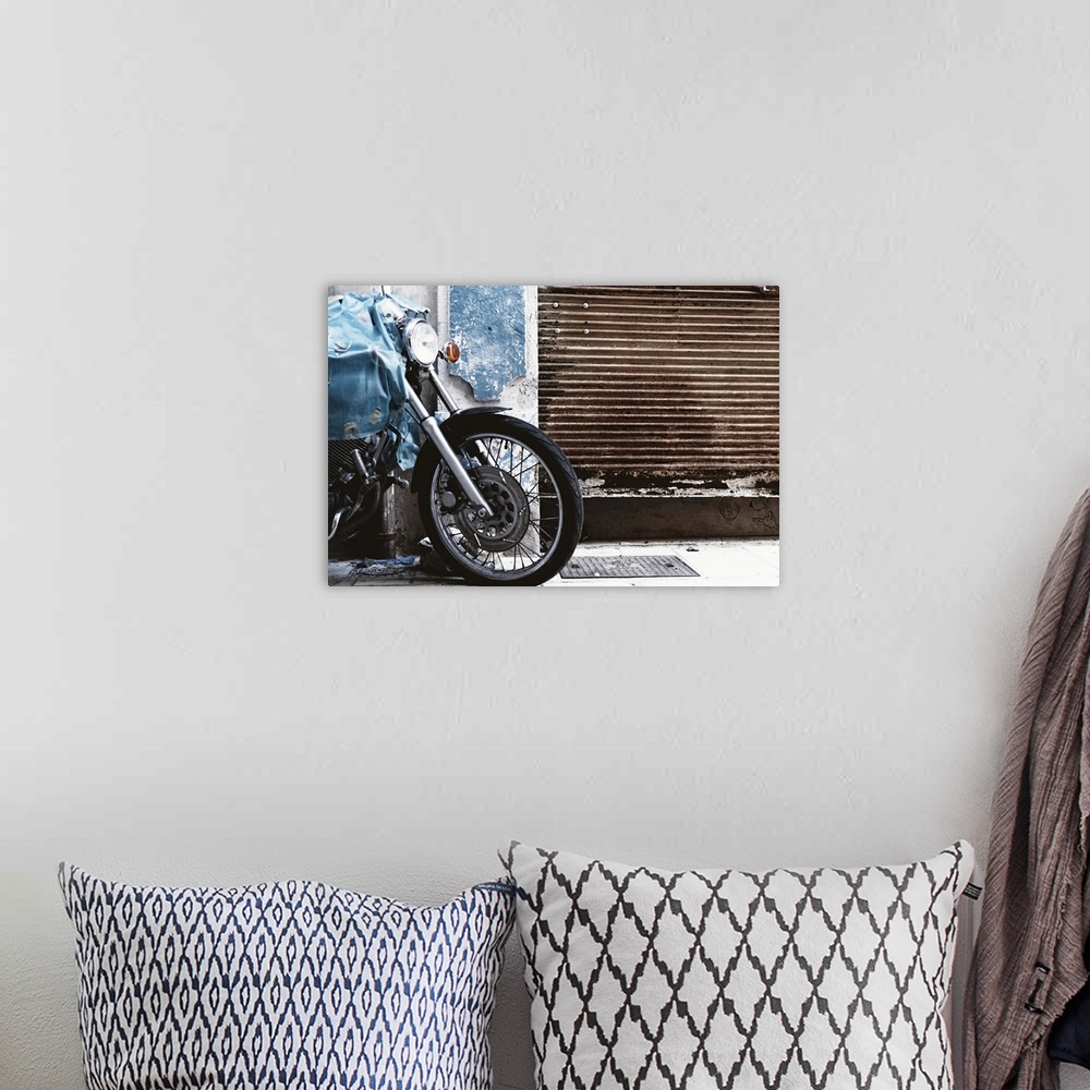 A bohemian room featuring Parked motorcycle with rusty garage door.