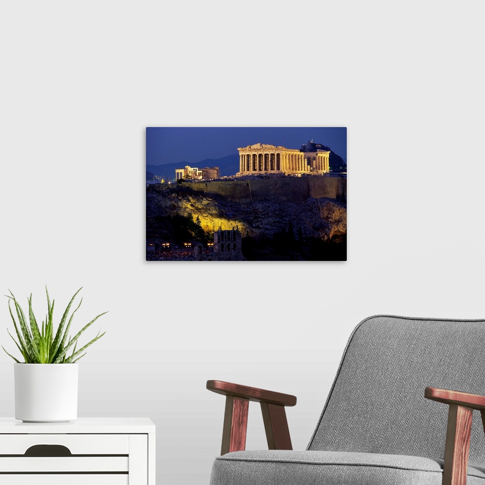 A modern room featuring The Parthenon and surrounding temples of the Acropolis sit illuminated, overlooking Athens.