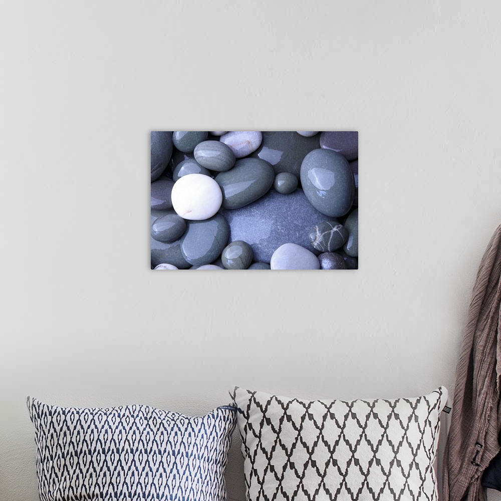 A bohemian room featuring Close up photo of wet, smooth stones in varying oval shapes and gray colors.