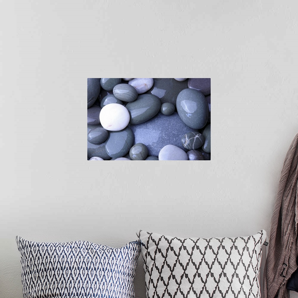 A bohemian room featuring Close up photo of wet, smooth stones in varying oval shapes and gray colors.