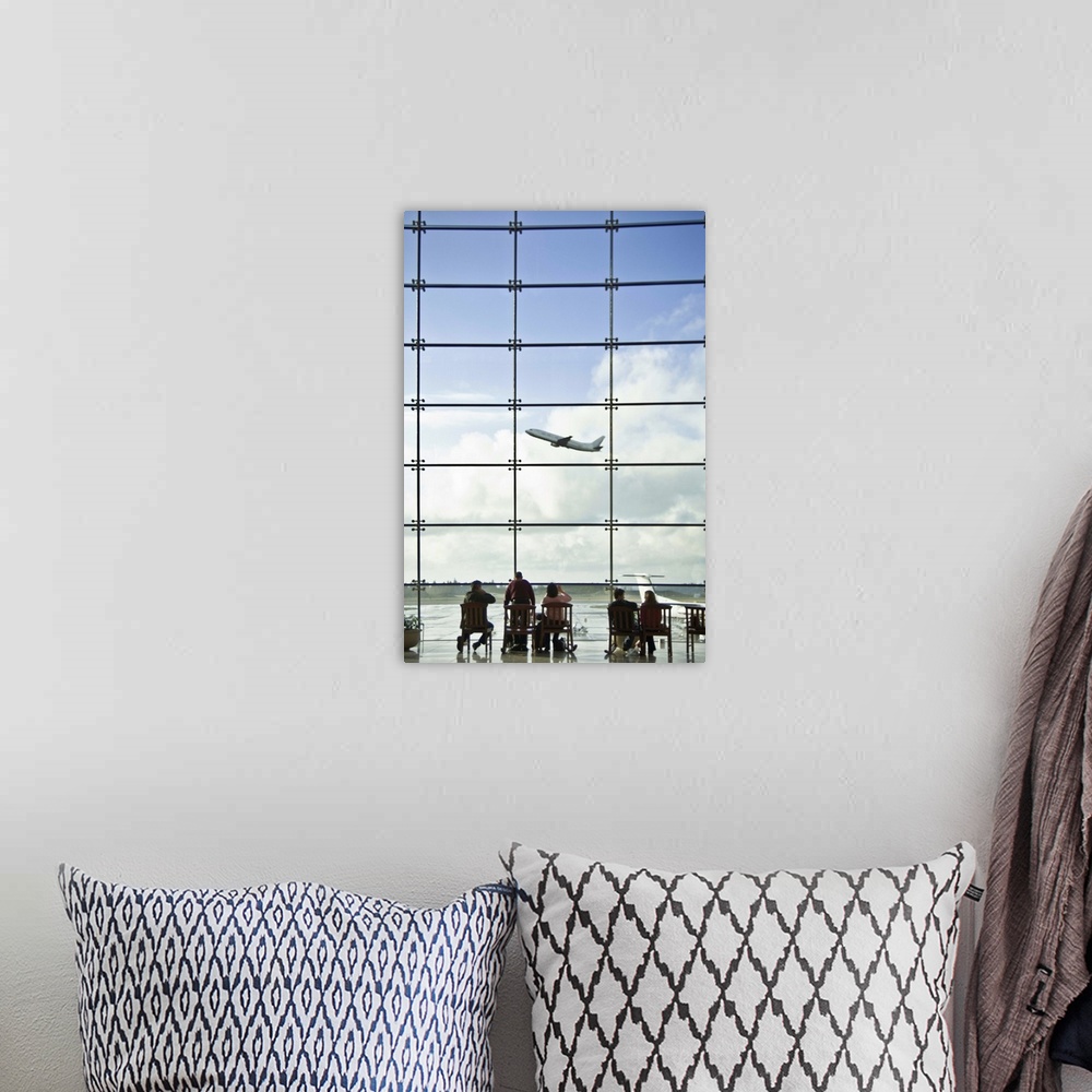 A bohemian room featuring People sitting in airport lobby and looking at airplane taking off