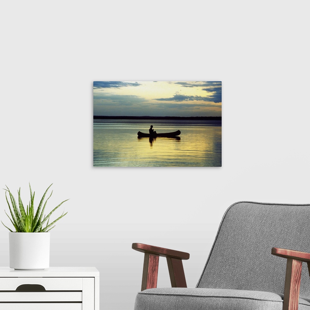 A modern room featuring Person on a canoe in a lake at sunset