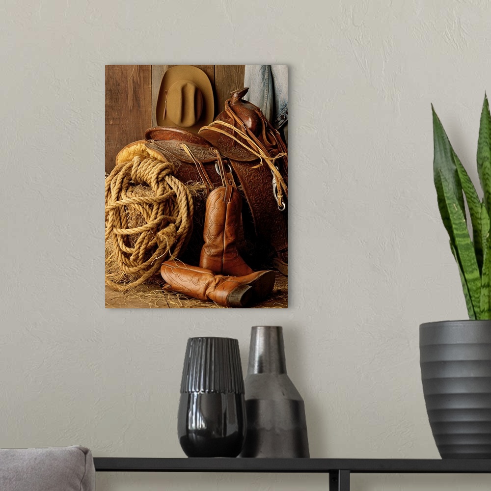 A modern room featuring Staged photo of a horse saddle on a bale of hay surrounded by other Cowboy necessities such as a ...