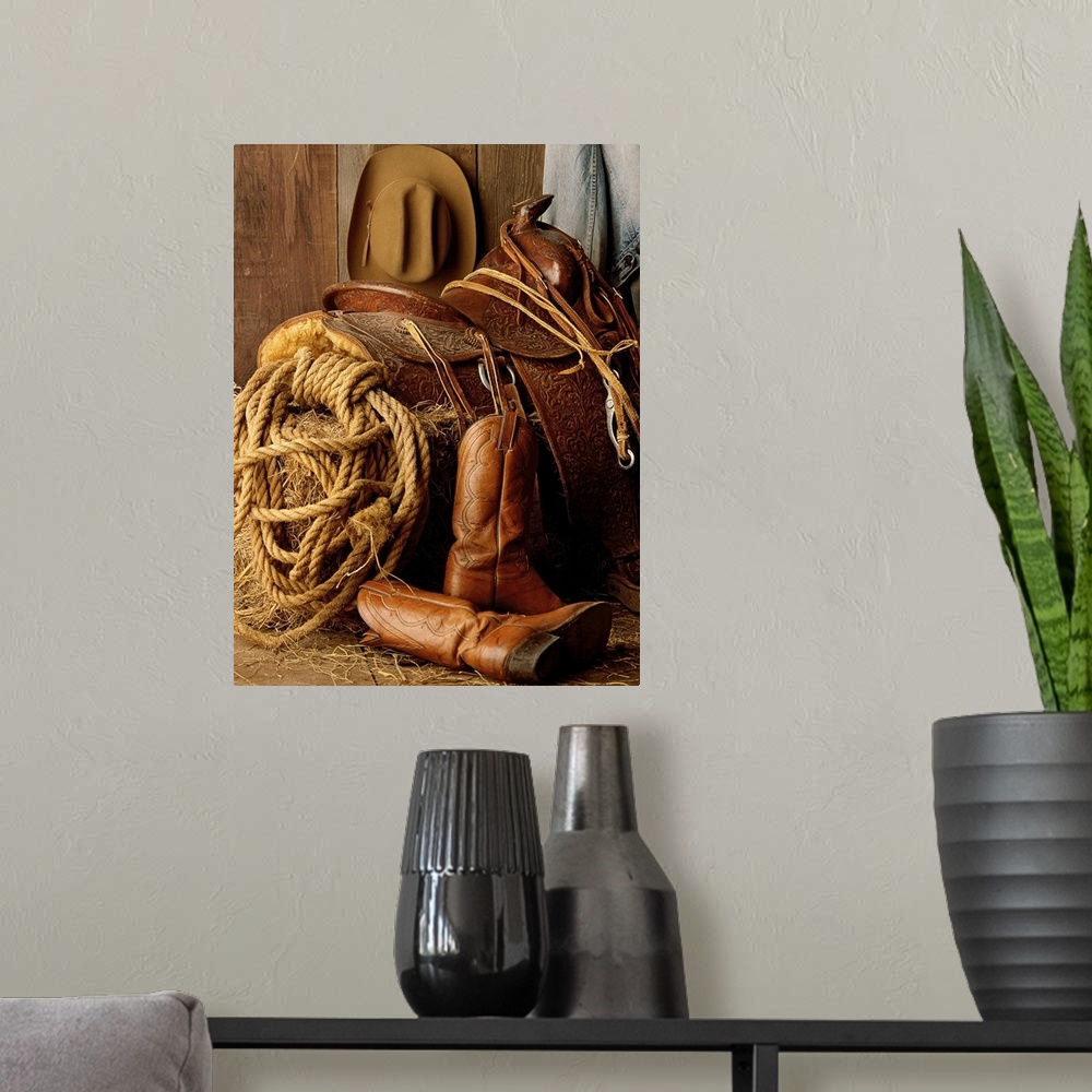 A modern room featuring Staged photo of a horse saddle on a bale of hay surrounded by other Cowboy necessities such as a ...