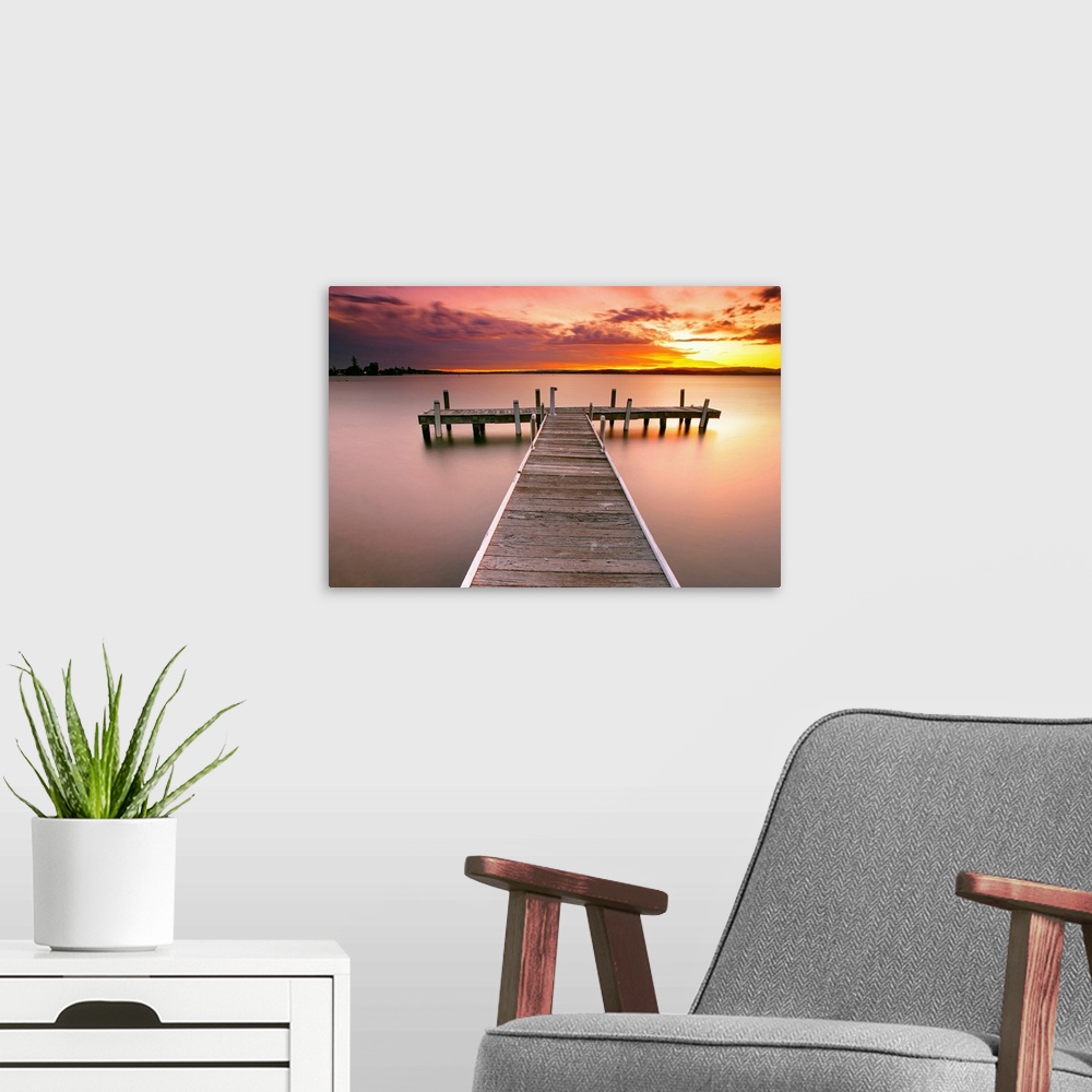 A modern room featuring Photograph of pier stretching into the ocean at dusk.  The sky is colorful from the setting sun a...