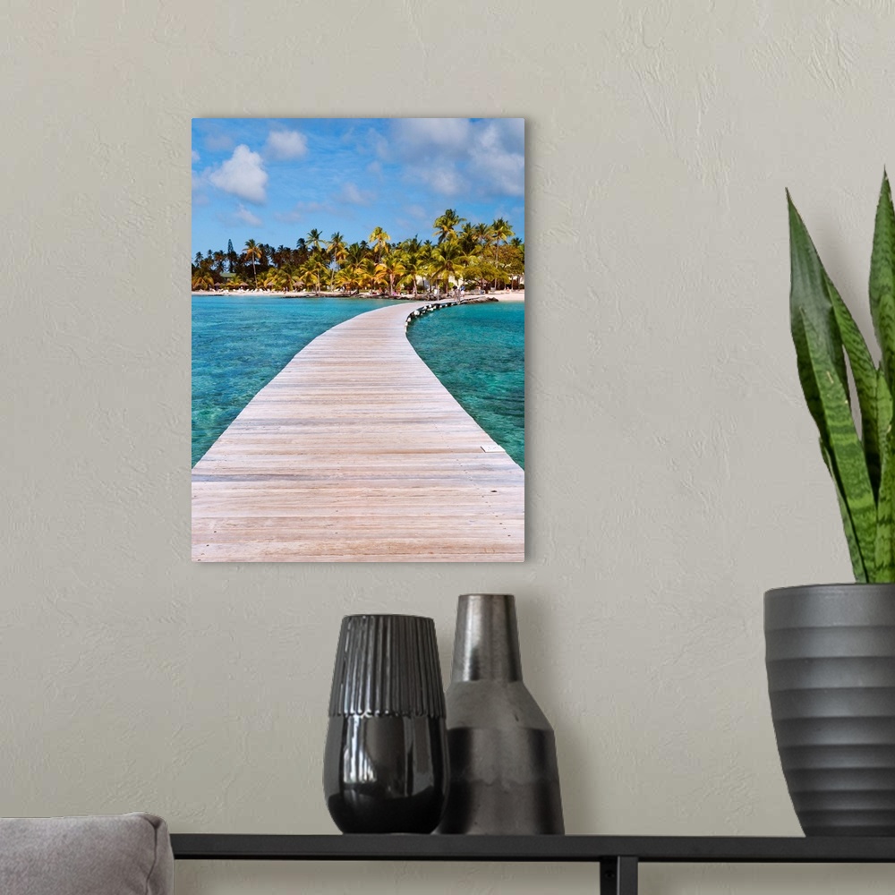 A modern room featuring Vertical photograph on a big canvas of a wooden path over clear blue waters, leading toward a tro...