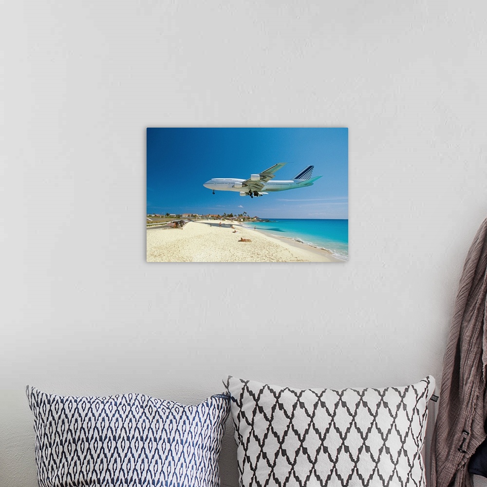 A bohemian room featuring This is a landscape photograph of a passenger jet flying low over a tropical beach preparing to l...